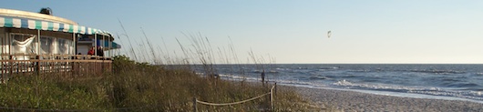 Enjoy your food and drinks right by the water, kiteboarder in the background